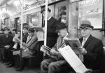 Pessoas lendo jornal no trem